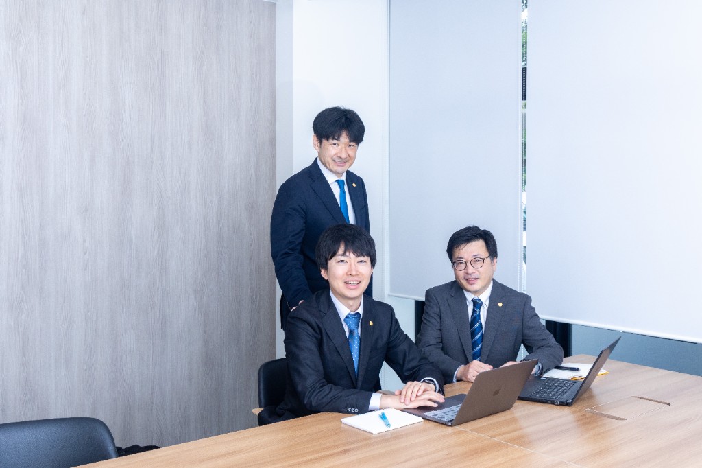 会議室でノートPCを囲み打ち合わせするコンサルタントチーム